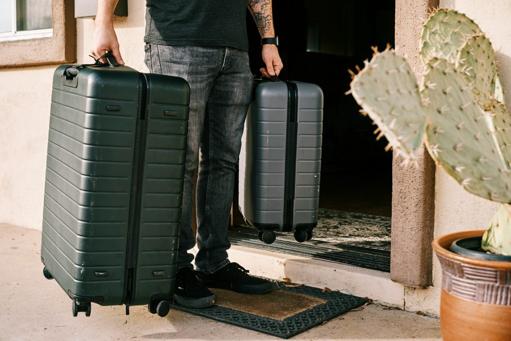 A person carrying suitcases for a trip after packing